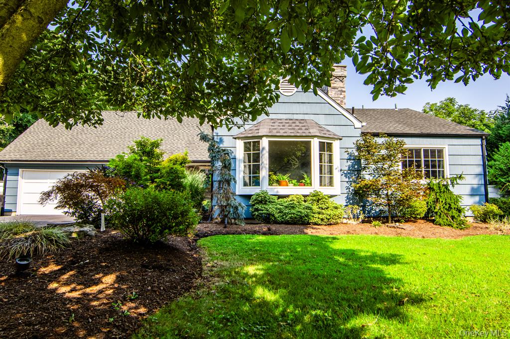 A landscaped West Nyack home with a white exterior and mature trees